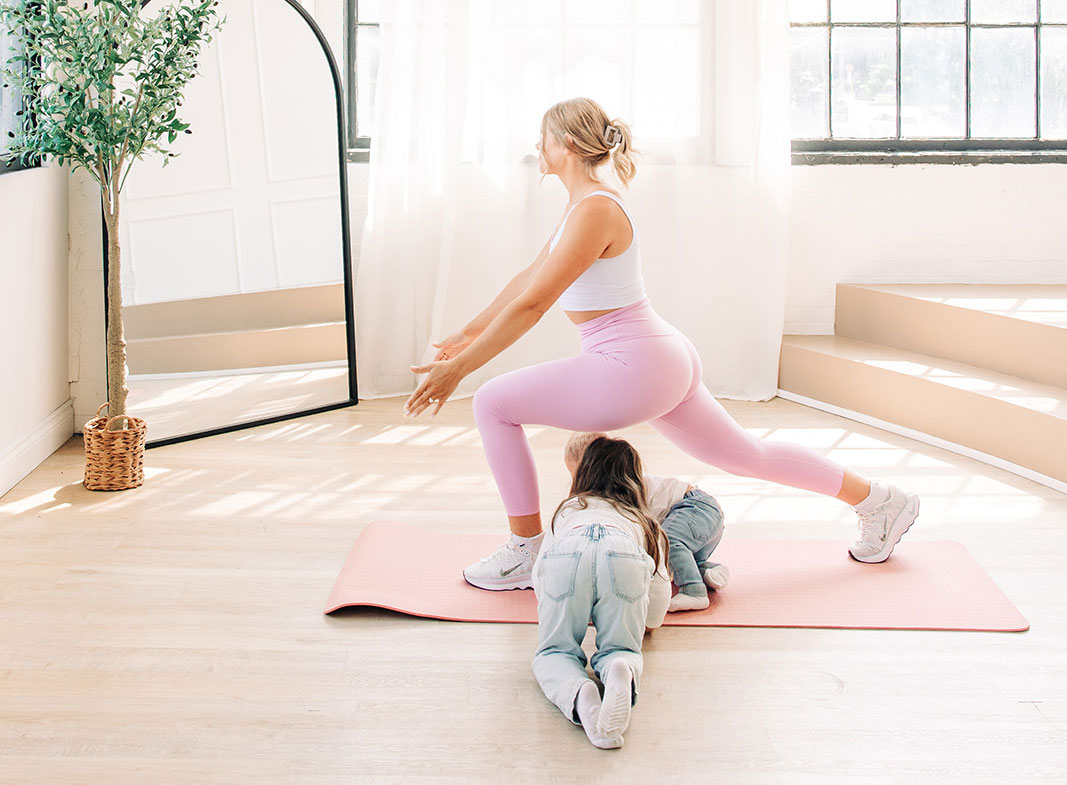 The coach is excercising while 2 kids are under her legs. 
